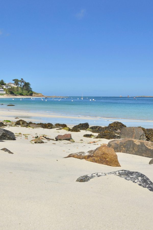 view-of-a-beach-with-fine-white-sand-and-rocks-in-front-of-blue-water-in-brittany-france