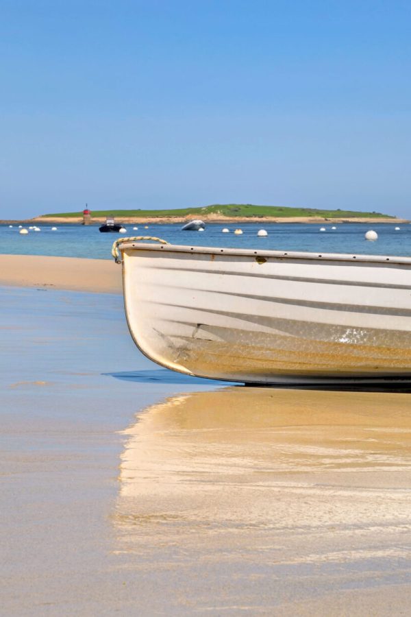 white-boat-placed-on-the-sand-near-the-blue-sea-with-reflection-on-the-wet-sand